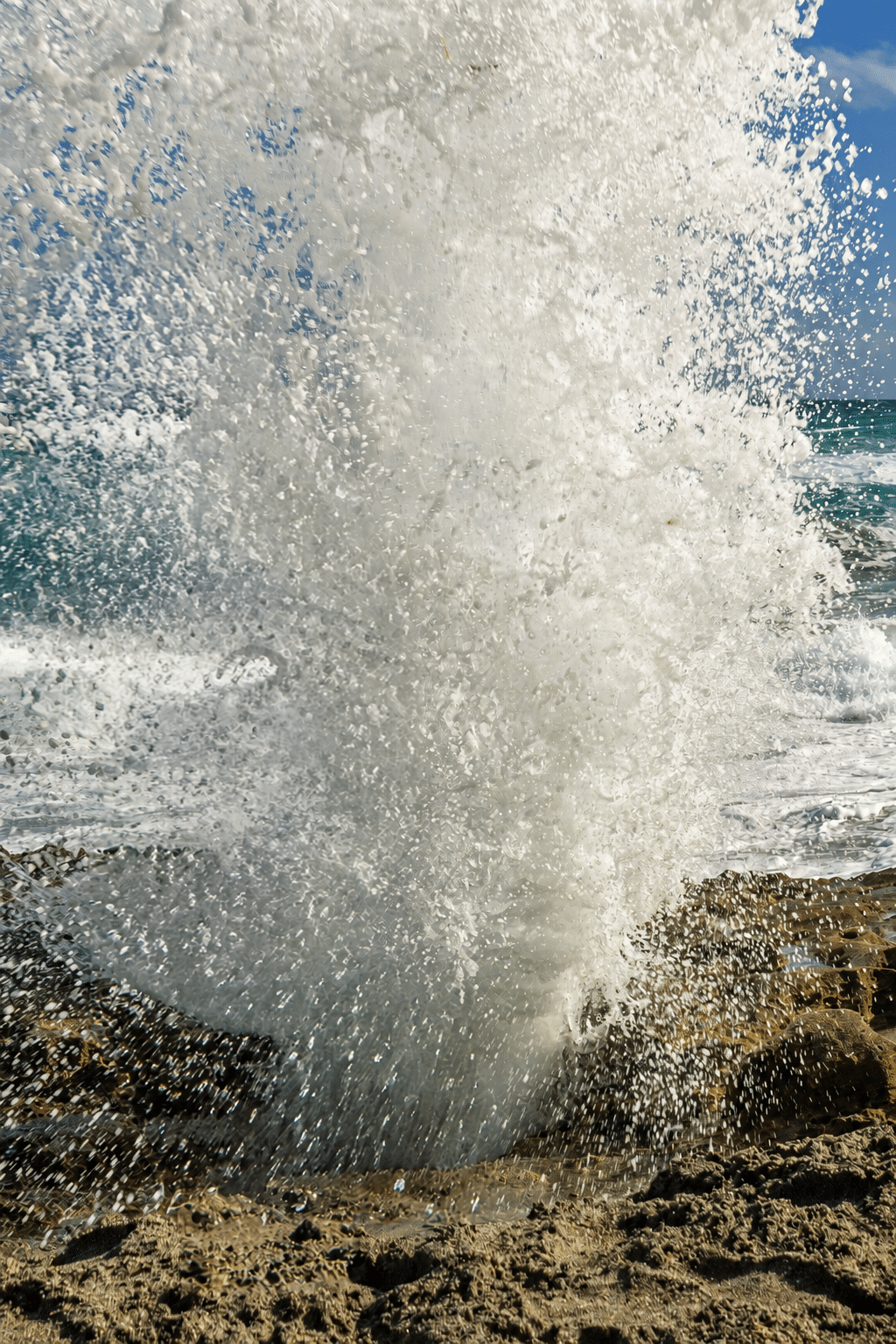 Blowing Rocks Preserve on Jupiter Island, Florida, with a large ocean wave crashing over the rocky shoreline. The Nature Conservancy.